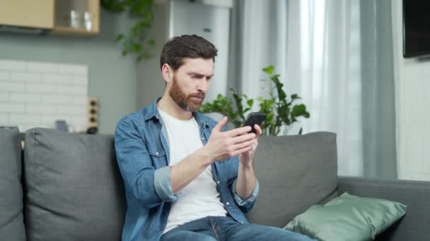 愤怒的年轻胡子男人有问题的智能手机在家里 男性压力大 使用失去连接的手机时 没有信号错误 也没有应用错误 — 图库视频影像