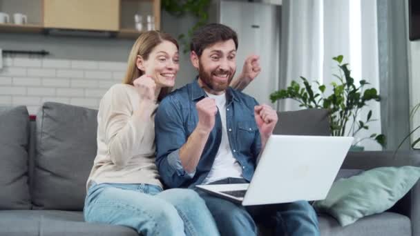 自宅でノートパソコンでメッセージを読んだ後 非常に幸せな素晴らしい幸運なカップル興奮した若い家族は 画面を見て 喜んで喜びはコンピュータ上で素晴らしいニュースを受けました成功の瞬間 — ストック動画