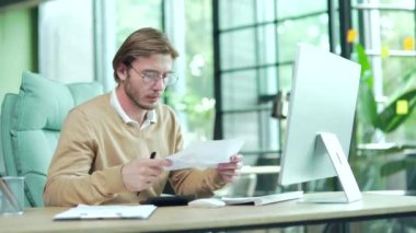 Endişeli genç iş adamı ofis çalışanı modern ofisteki evrak işleriyle ilgili sorunlar yaşıyor. Çalışanlar, iş yerlerindeki istatistik raporlarının analiz edilmesiyle yorgun düşüyor. 
