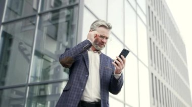 Hüzünlü yetişkin işadamı, banka finansal sorunları olan bir mesaj aldı. Modern iş merkezindeki cep telefonuyla yapılan anlaşmayla. Zararlı adam dışarıda akıllı telefondan kötü haberler okuyor.