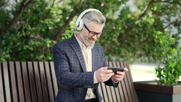 Πορτρέτο Ενθουσιασμένοι Γενειοφόρος Επιχειρηματίας Gamer Ακουστικά Κάθεται Στον Πάγκο Χαλαρώνοντας — Αρχείο Βίντεο
