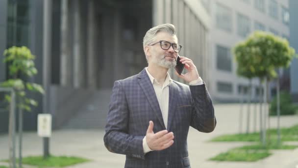 Przystojny Dojrzały Biznesmen Okularach Rozmawiający Przez Telefon Nowoczesnym Centrum Biznesowym — Wideo stockowe