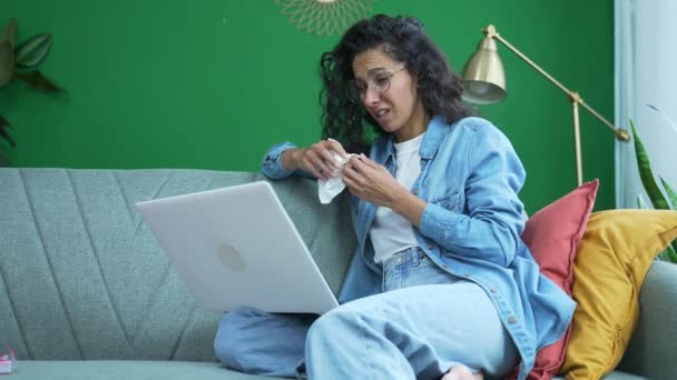 若い女性は リビングルームでソファに座っているオンラインカウンセリングセッションで精神療法士と話す泣いている家庭でラップトップコンピュータによる心理的なサポートで問題を議論 — ストック動画