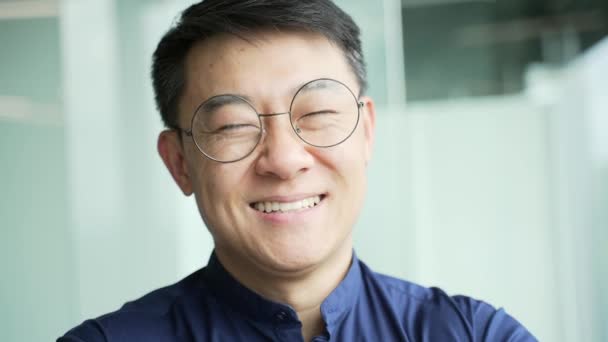 近代的なオフィスでカメラを見てメガネを持つ笑顔のItスペシャリストプログラマーの肖像画を閉じます屋内だけで開発会社でアジアの起業家の専門家の開発者のヘッドショット — ストック動画