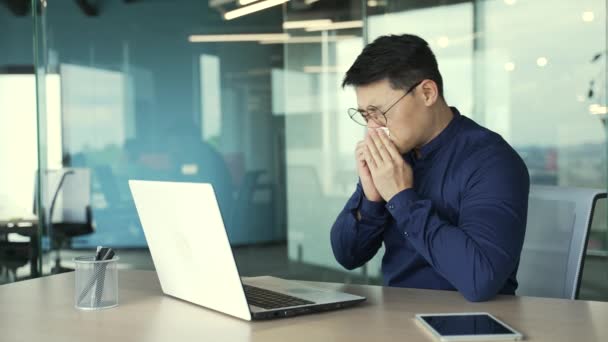 オフィスでラップトップコンピュータで作業中に鼻のくしゃみや咳を実行している病気のビジネスマンItプログラマー職場でインフルエンザウイルスの症状を得る不健康なアジアの労働者寒さと熱の概念 — ストック動画