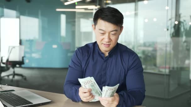 成功した笑顔アジアの実業家の雇用主は 現金のお金のカウントを保持し 屋内カメラに手を差し伸べますお金を与える支払いや収入を提供する自信のItプログラマ共有投資の概念 — ストック動画