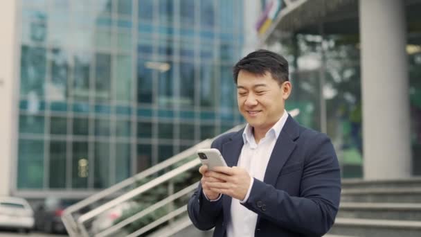 Retrato Empresario Asiático Guapo Sostiene Teléfono Inteligente Desplazamiento Navegación Mensajes — Vídeos de Stock