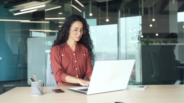 ブルネットの従業員はラップトップコンピュータに焦点を当てた職場で現代的なオフィスで働いており 自信のある女性プログラマーウェブ開発者がプログラミングコードを書くビジネス女性労働者をカジュアルにプログラミング — ストック動画