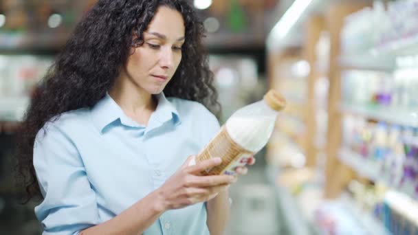 Hispanic Woman Chooses Dairy Products Holding Bottle Milk Her Hands — Vídeo de stock