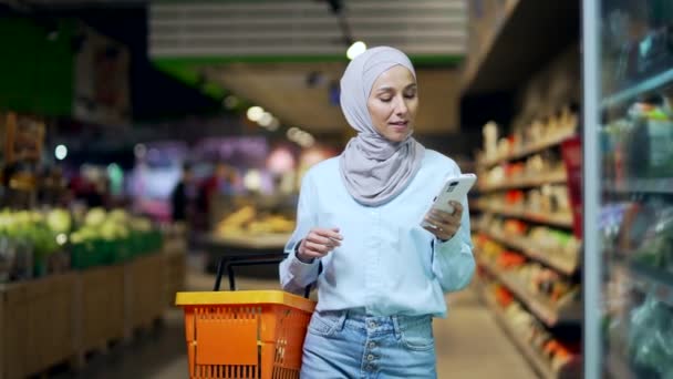 Молодая Мусульманка Хиджабе Покупатель Покупатель Проверяет Список Покупок Помощью Смартфона — стоковое видео