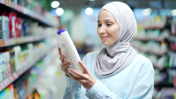 Muslimske Kvinde Hijab Undersøger Sammensætningen Produktet Shampoo Kvinde Kundelæsningsetiket Kosmetikflaske – Stock-video