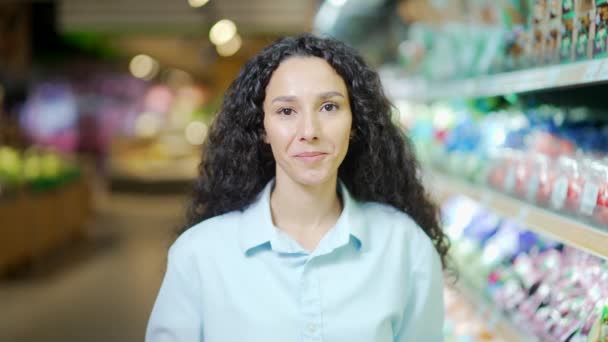 スーパーマーケットや食料品店の幸せな女性のバイヤーの肖像カメラと笑顔を見て満足かなりブルネットのパニック女性の顧客は 食品市場で撮影されたハイパーマーケットの頭の中でポーズ屋内 — ストック動画