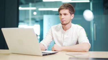 Focused concentrated developer typing on laptop in at workplace in office. Pensive thoughtful young entrepreneur using computer working over business project Doing online data market analysis thinking