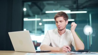 Focused concentrated developer sit at desk look at laptop in at workplace in office. Businessman thinking on solutions for work. Pensive thoughtful young entrepreneur working over business project