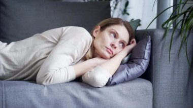 sad depressed lonely woman lying on the couch alone at home. Apathetic tired lazy lady sleeping on sofa at home alone. Depressed suffering from psychological problem trouble 