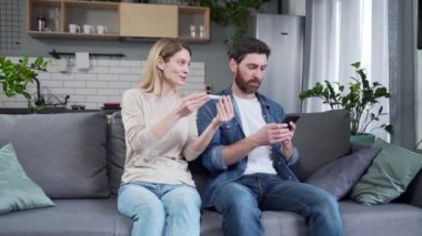 Genç, gülümseyen bir kadın kocasına pozitif hamilelik testi gösteriyor ve ailesi oturma odasında bir bebek beklediği için seviniyor. Gelecekteki ebeveyn olacağı için çok heyecanlı bir erkek karısına evde sarılıyor.