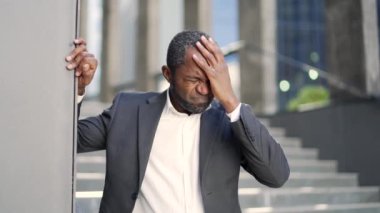 Yorgun Afro-Amerikalı olgun bir adam baş ağrısından muzdarip. Ofis binasının önünde dikiliyor. Resmi takım elbiseli hasta, orta yaşlı bir işadamı elini başına dayadı. Migreni var.