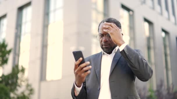 Verärgerter Afrikanisch Amerikanischer Geschäftsmann Schaut Schockierende Sms Während Sein Smartphone — Stockvideo