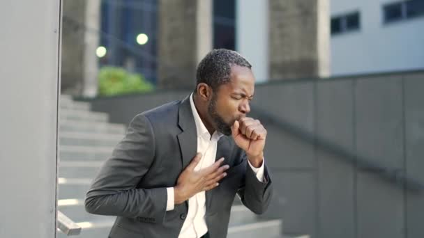 一位非洲裔美国成熟男子 站在一幢办公楼前咳嗽 疲惫的中年商人 身穿正装 抱着胸膛 身患病毒 — 图库视频影像