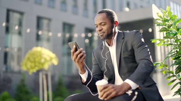 African American Mature Man Headphones Using Smartphone While Sitting Bench — стокове відео