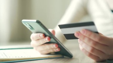 close up of woman hand making payment using credit card and mobile phone Closeup young female shopping online banking order indoors customer paying on smartphone purchase ecommerce money transaction