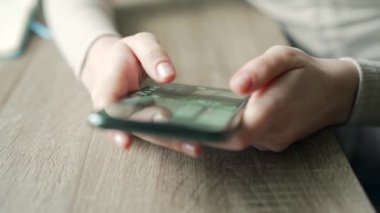 Akıllı telefon tutarken sosyal ağda kayan bir kadının el fotoğrafı. Kapalı alanda cep telefonu kullanan genç bir kadın.