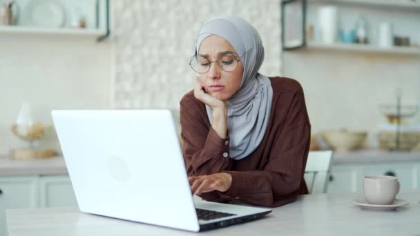 悲しいです孤独な退屈イスラム教徒の女性でHihab感じ退屈でラップトップコンピュータでキッチンアップ不安女性とともにガラス苦しみうつ病重度の不安不足動機の自宅で孤独概念 — ストック動画