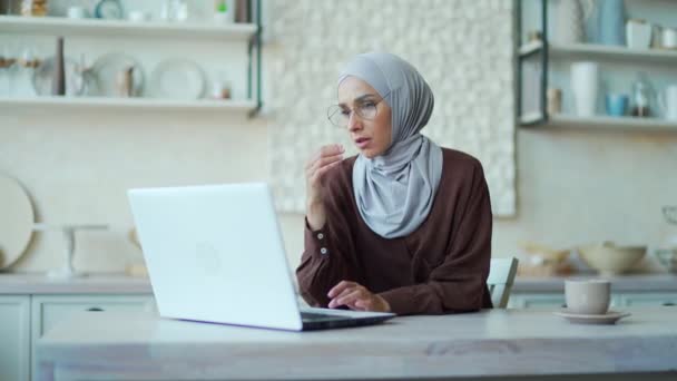 疲れたイスラム教徒の女性は自宅のノートパソコンで仕事をしながら目の痛みを感じる 女性のフリーランサーは疲れとストレスに苦しんでいますメガネのゴム目の緊張貧弱な視力頭痛片頭痛 — ストック動画