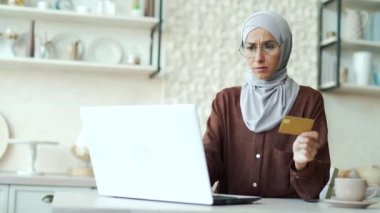 Confused young muslim woman in hijab with credit card having problem with online order payment error fraud or blocked bank account Stressed female doing shopping at internet money transfer withdrawal