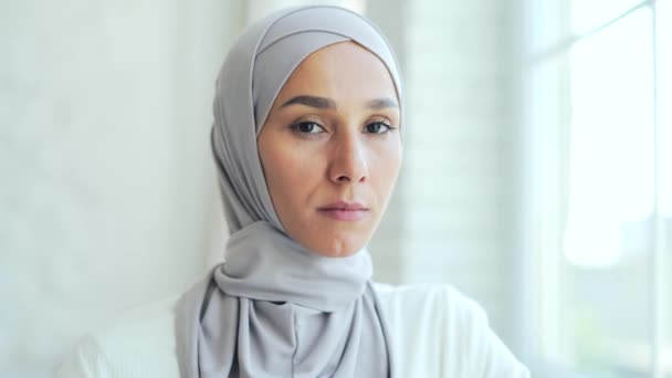 特写一个严肃而自信的穆斯林女青年头像 头像是一位伊斯兰女性的头像 她凝视着相机 背景明亮 脸色苍白 — 图库视频影像