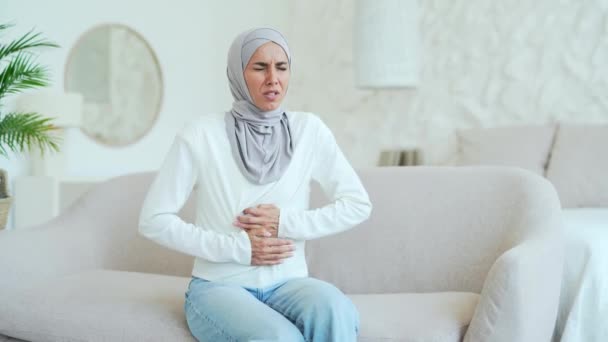 Doente Jovem Muçulmana Hijab Sofrendo Dor Estômago Sentado Sofá Segurando — Vídeo de Stock