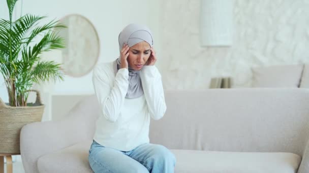 Mulher Muçulmana Jovem Infeliz Hijab Sentado Sofá Esfrega Templo Com — Vídeo de Stock