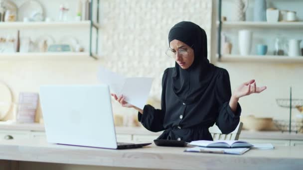 眼鏡を持つ心配若いイスラム教徒の女性は 光熱費の請求書のレビューと計算を管理し 債務や支払いの問題を持っています財務管理書類の概念 — ストック動画