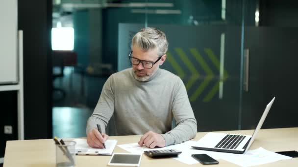 Mature Gray Haired Bearded Businessman Glasses Calculating Calculator Writing Notebook — 图库视频影像