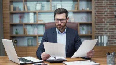 Happy young bearded mature business man investor with glasses reading mail work letter document with great news celebrating victory success in project work or salary increase at office workplace