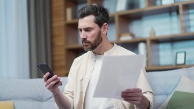 Sinirli, olgun, sakallı bir adam akıllı telefon aletinin faturalarını ödemekte zorlanıyor. Sinirli bir erkek, kapalı alanda internet üzerinden ödeme yapamadı. Kötü servis kavramı.
