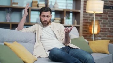Portrait of worried mature emotionally man sitting on couch in the living room at home Sad depressed male feels unhappy by difficulties at work break up or hard divorce Mental health problem concept