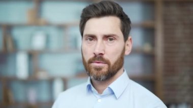 Close up portrait face of confident bearded businessman investor looking at the camera at modern office workplace Successful attractive serious entrepreneur owner in light blue shirt indoors alone
