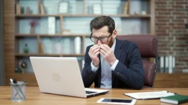 Sick business man investor blowing running nose sneeze and cough while working on laptop computer at office Unhealthy entrepreneur getting flu virus symptom at modern workplace Cold and fever concept 