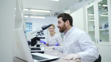 Overjoyed mature man scientist with protective gloves extremely happy after research with microscope at microbiology pharmaceutical biochemistry laboratory indoor Discovery success in research concept
