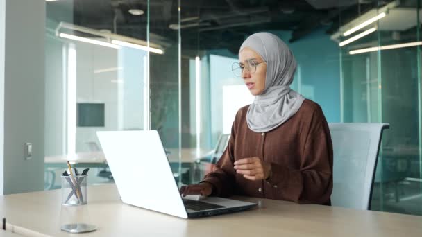ヒジャーブ州のイスラム教徒のビジネス女性起業家は 現代のオフィスの職場でエアコン冷却システムや加湿器の高温の問題のため コンピュータ作業中に熱く感じる — ストック動画