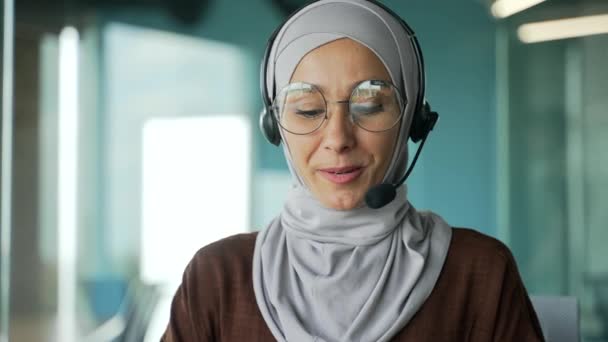 在现代办公室的工作场所 用无线耳机看摄像头 通过在线会议视频交谈的穆斯林女企业家支持经理的网络摄像头图像 — 图库视频影像