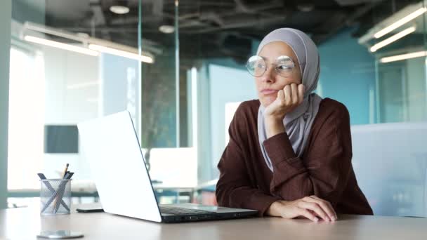 現代の職場でコンピュータを使用して長い一日を持っているヒジャーブの怠惰なイスラム教徒のビジネス女性を退屈やる気のないオフィスワーカー起業家は キーボードだけで室内でテキストメッセージやブラウジングを入力しようとします — ストック動画