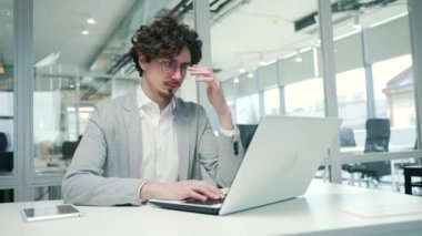 Portrait of sad business man freelancer suffering headache painful feelings chronic migraine pressure working on computer at modern glass office Stressed entrepreneur feels hurt at workplace indoors