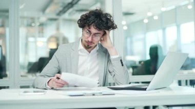 Worried nervous business man freelancer has problems with paper work document at modern office Stressed bearded man with glasses feeling exhausted with statistics reports analysing data at workplace