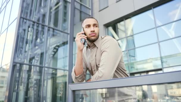 オフィスビルの前で男が電話で話している ビジネス会話スマートフォンを屋外で使用してシャツの男性エグゼクティブマネージャー 市内で成功し 忙しい男 都市生活 — ストック動画
