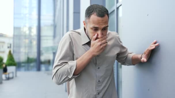 若い男がオフィスビルの外に立っていて 吐き気や嘔吐の症状を経験している 病気の原因は食中毒 消化不良 感染症かもしれません — ストック動画