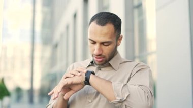 Bir ofis binasının yanında sokakta dikilirken akıllı saatle konuşan tişörtlü bir delikanlıyı yakından çek. Yakışıklı melez Afro-Amerikan erkeği arkadaşlarıyla konuşurken gülümsüyor.