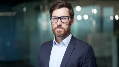 Ciddi bir yüz ifadesi olan yakışıklı bir erkek portresi. Kafkasyalı bir adamın kamera görüntüsü. Modern ofis geçmişi bulanık.