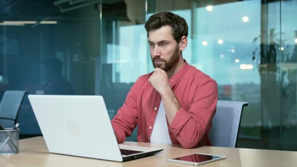 集中的成熟商人企业家在笔记本电脑行业工作 思考如何解决创业问题 并在玻璃现代办公室的工作场所把忙碌英俊的男性投射到红衫上 — 图库视频影像